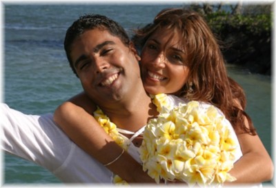 bride holding the groom with the yellow plumeria bouquet at Waialae beach park